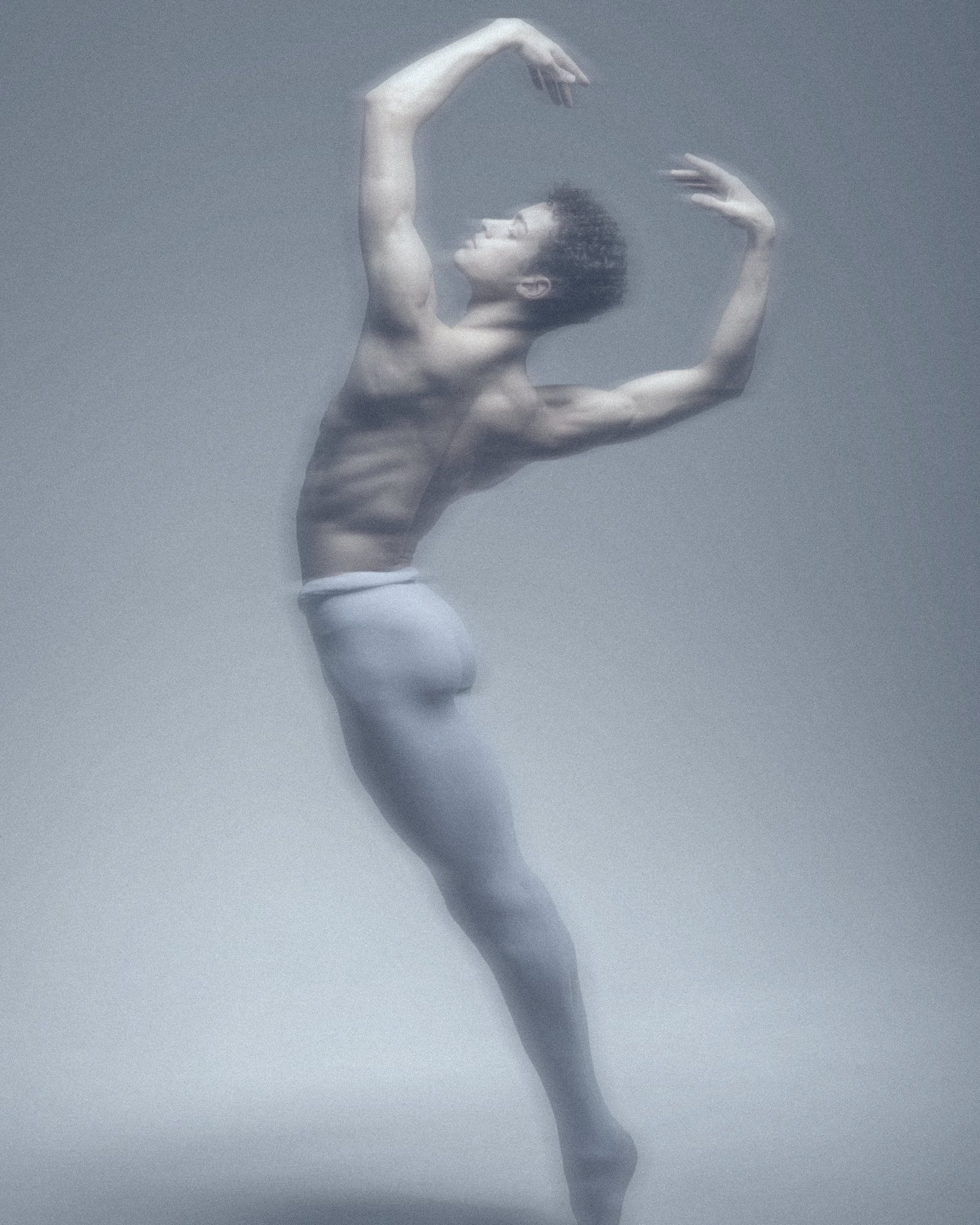 A ballet dancer leaping in pale blue light