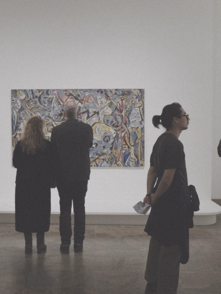 Visitors looking at a painting in a gallery