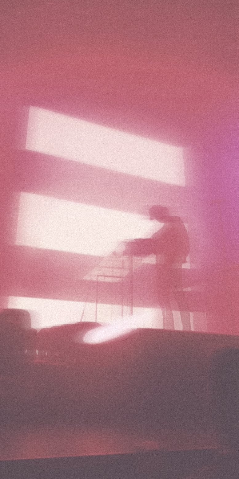 A performer silhouetted against soft pink light