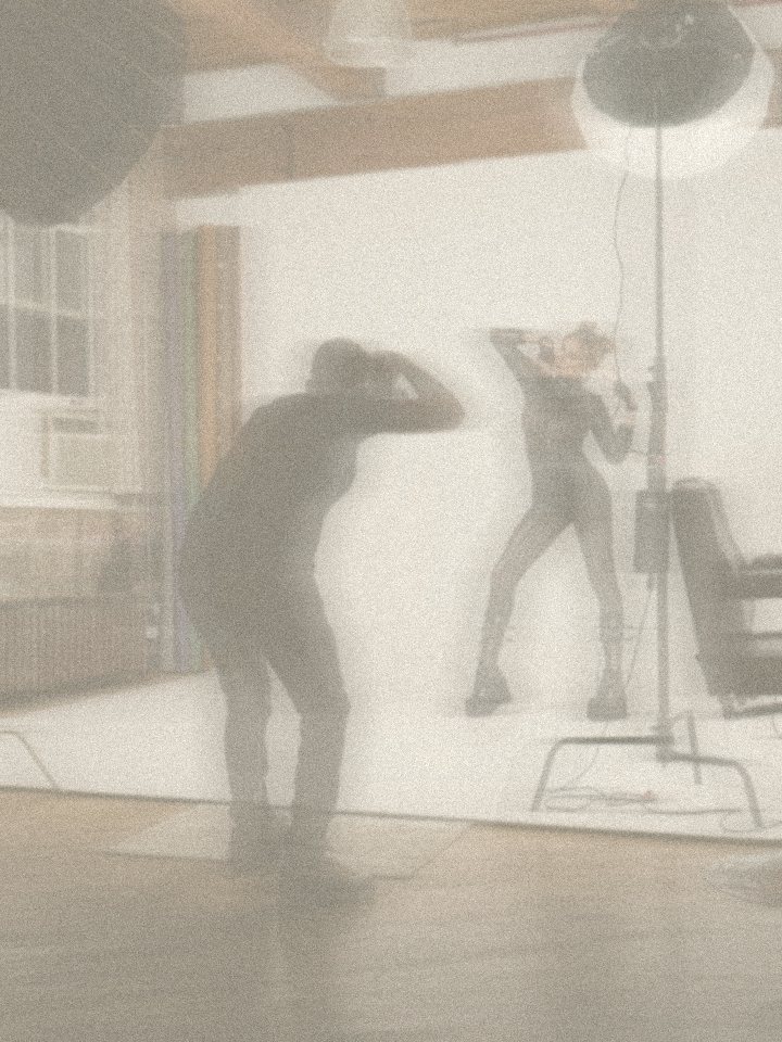 A photographer shooting a model in a cream studio